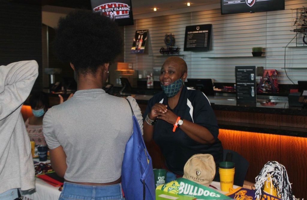 A representative engages with attendees at an event, discussing initiatives related to HBCUs and educational support.